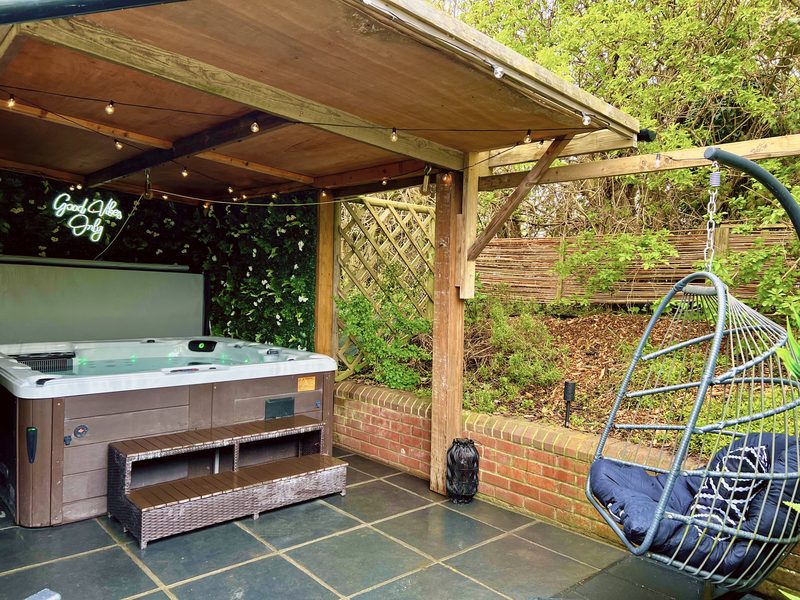The hot tub under its gazebo, with the hanging egg chair